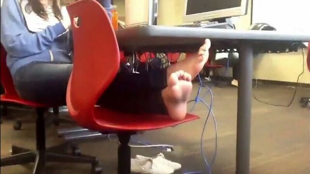 A girl sits in the office with a tablet with her feet on a chair