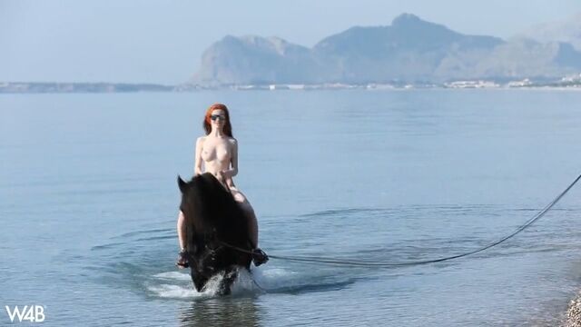 Red-haired woman in nature with a handsome stallion